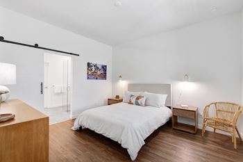 A bedroom with a bed and a dresser and a door to a bathroom